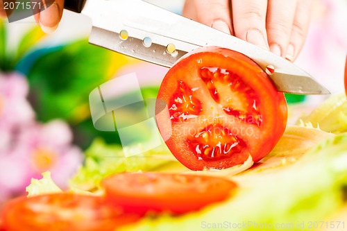 Image of Woman's hands cutting tomato