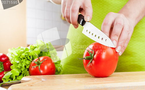 Image of Woman's hands cutting tomato