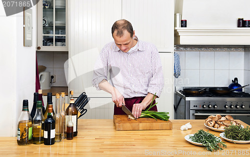 Image of Man Cutting Spring Onions In Kitchen