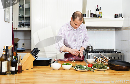 Image of Man Cutting Meat On Chopping Board