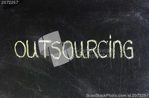 Image of outsourcing word in white chalk handwriting on blackboard 