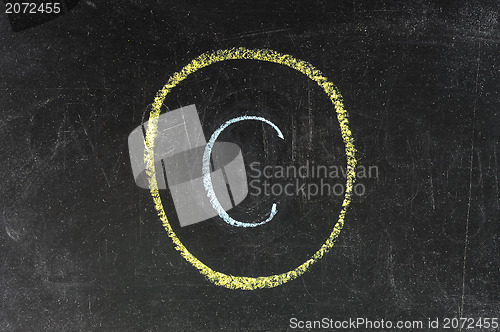 Image of copyright symbol sketched with white chalk on blackboard 