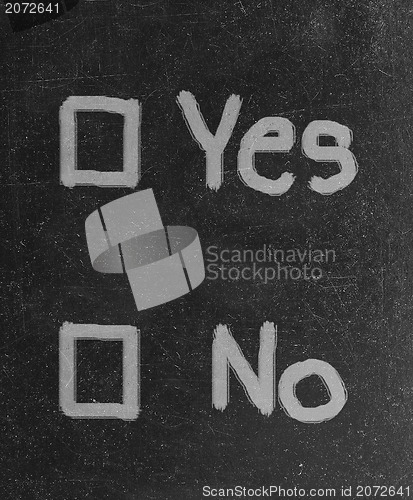 Image of yes and no check boxes sketched with white chalk on blackboard with eraser smudges 