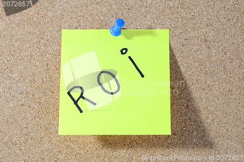 Image of The word ROI Note paper with push pins on noticeboard 