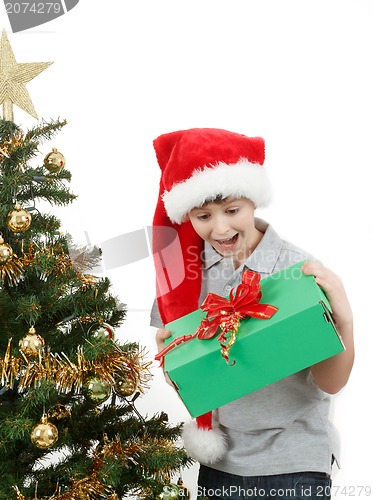 Image of happy boy in santa hat surprised by christmas present