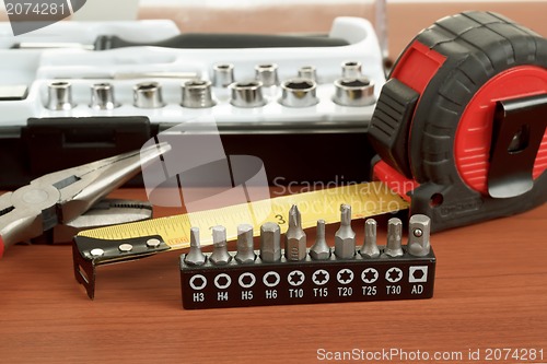 Image of screwdriver toolbox with set of bits, pliers and measuring tape