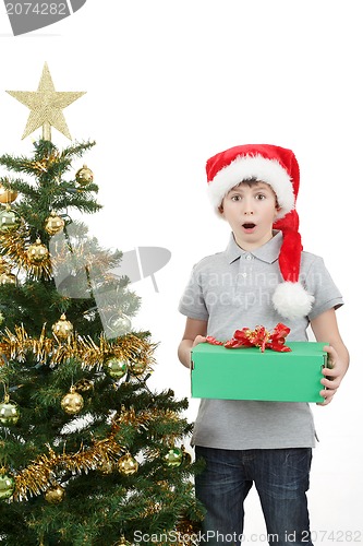 Image of happy boy in santa hat surprised by christmas present