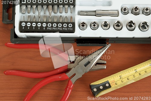 Image of screwdriver toolbox with set of bits, pliers and measuring tape