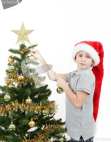 Image of Boy with santa hat decorates the Christmas tree