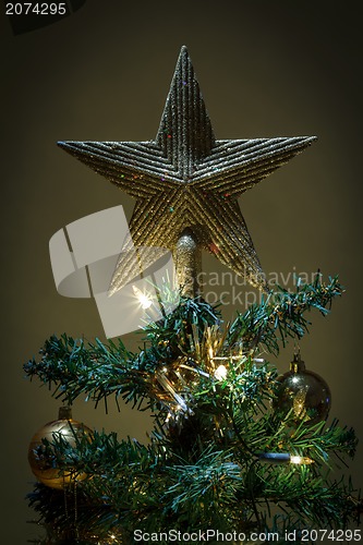 Image of christmas star on tree with yellow and green balls 