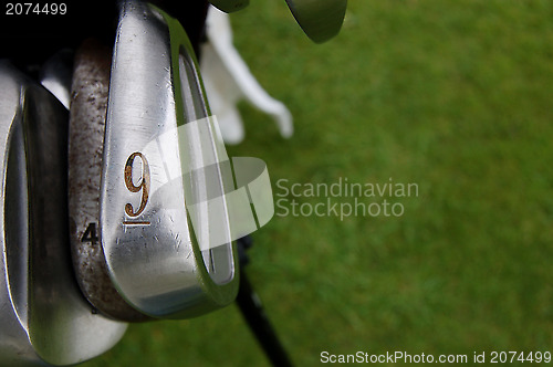 Image of Nine iron and golf clubs on the green