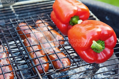 Image of Red sweet pepper and sausages on a grill, close up