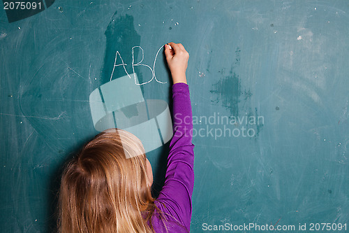 Image of Young girl writing letters on chalkboard