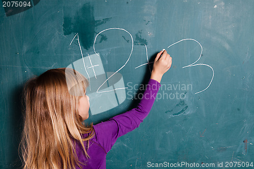 Image of Young girl writing numbers on chalkboard