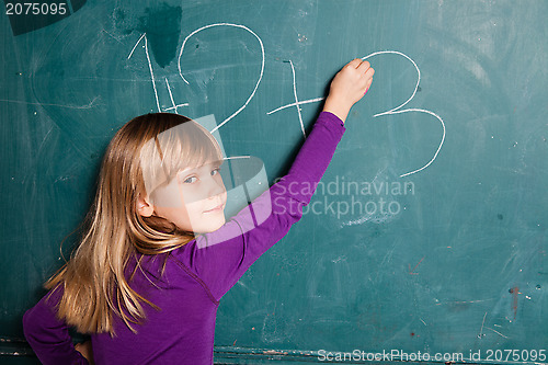 Image of Young girl writing numbers on chalkboard
