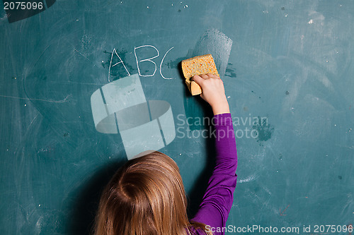 Image of Young girl wiping chalkboard with wet sponge