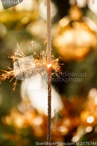 Image of burning sparkler and out of focus christmas tree 