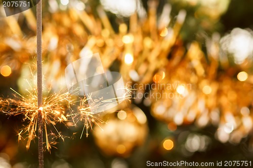 Image of burning sparkler and out of focus christmas tree 