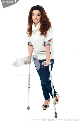 Image of Sad faced woman limping with crutches