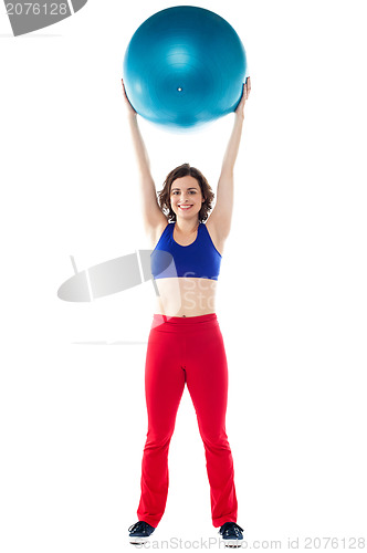 Image of Happy woman lifting pilates ball upwards