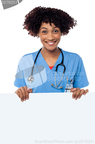 Image of Joyous female doctor standing behind ad board