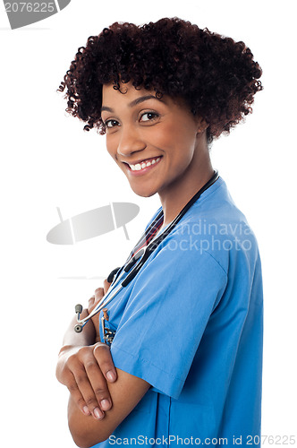 Image of Smiling female physician standing sideways with folded arms