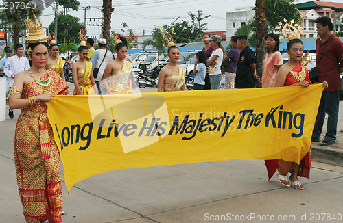 Image of Thai women in traditional dress carry a banner to pay respect to