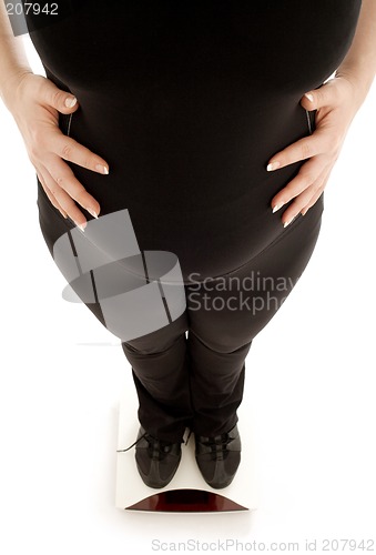 Image of pregnant lady weighing oneself, focus on belly