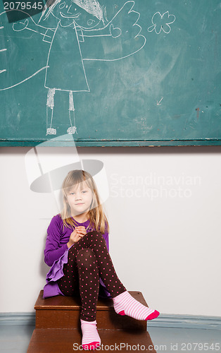 Image of Young girl sitting in front of chalkboard