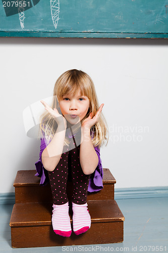 Image of Young girl blowing kiss in classroom