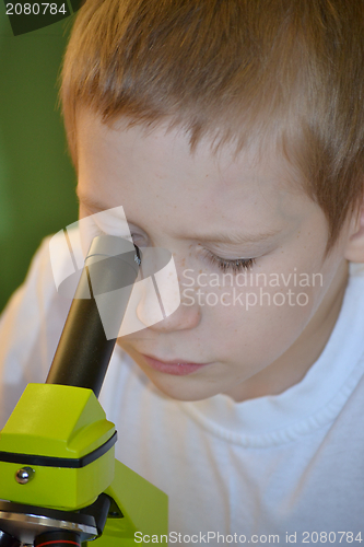 Image of the boy looks in a microscope