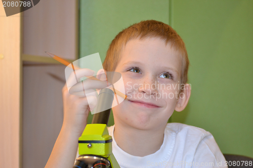 Image of the boy looks in a microscope