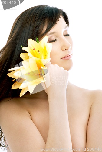 Image of brunette with yellow lily flowers in spa