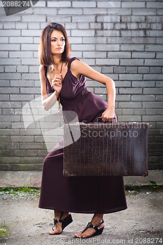 Image of beautiful thief girl with vintage suitcase waiting at the station