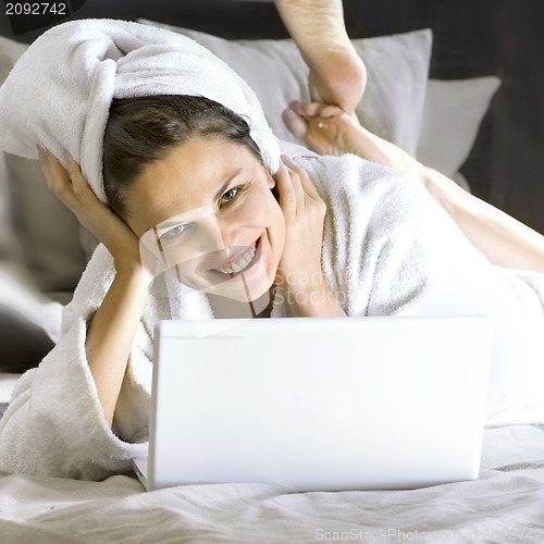 Image of happy woman on the bed with laptop