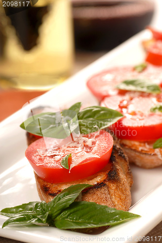 Image of Bruschetta with tomato, mozzarella and basil with a glass of win