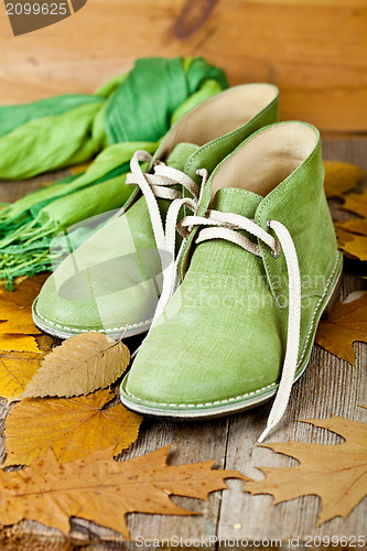 Image of green leather boots, scarf and yellow leaves 