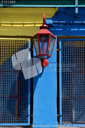 Image of red street lamp  and a yellow blue wall  in la boca