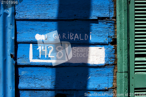 Image of green wood venetian blind and a blue garibaldi wall