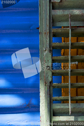 Image of green iron venetian blind and a blue metal wall