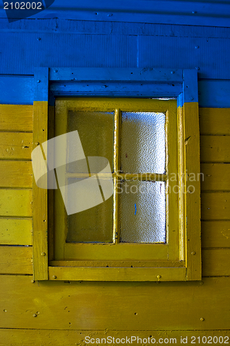 Image of old yellow window in blue wall 