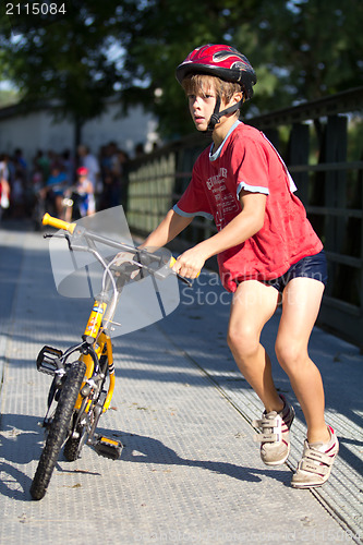 Image of Very young triathlete pushing his bike.