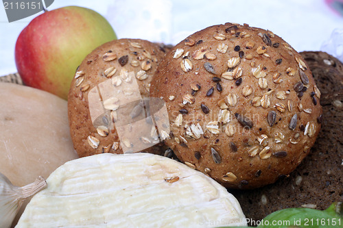 Image of Rustic still life of bread, cheese and apple in a wicker basket