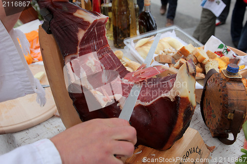 Image of A hand cutting prosciutto