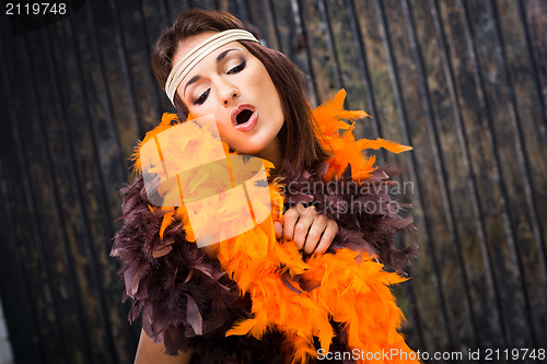 Image of singing actress in brown and orange boa