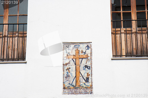 Image of Earthenware cross on a white facade.