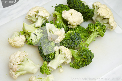 Image of cauliflower and broccoli pieces on white cutting board