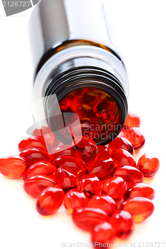 Image of Red capsules with vitamins spilled from the bottle.