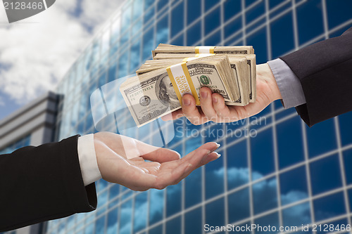 Image of Male Handing Stack of Cash to Woman with Corporate Building