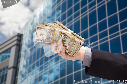 Image of Male Hand Holding Stack of Cash with Corporate Building